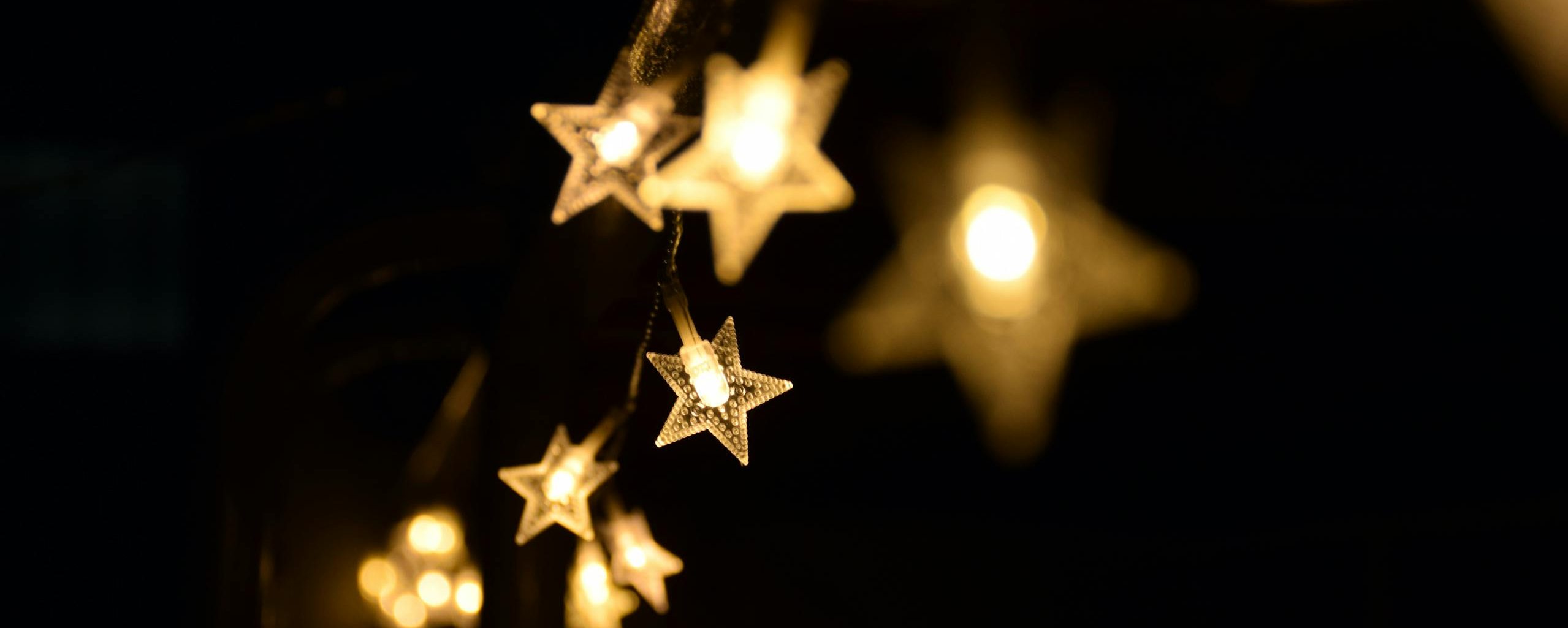 Warm star-shaped fairy lights hanging elegantly in the night, creating a festive ambiance.